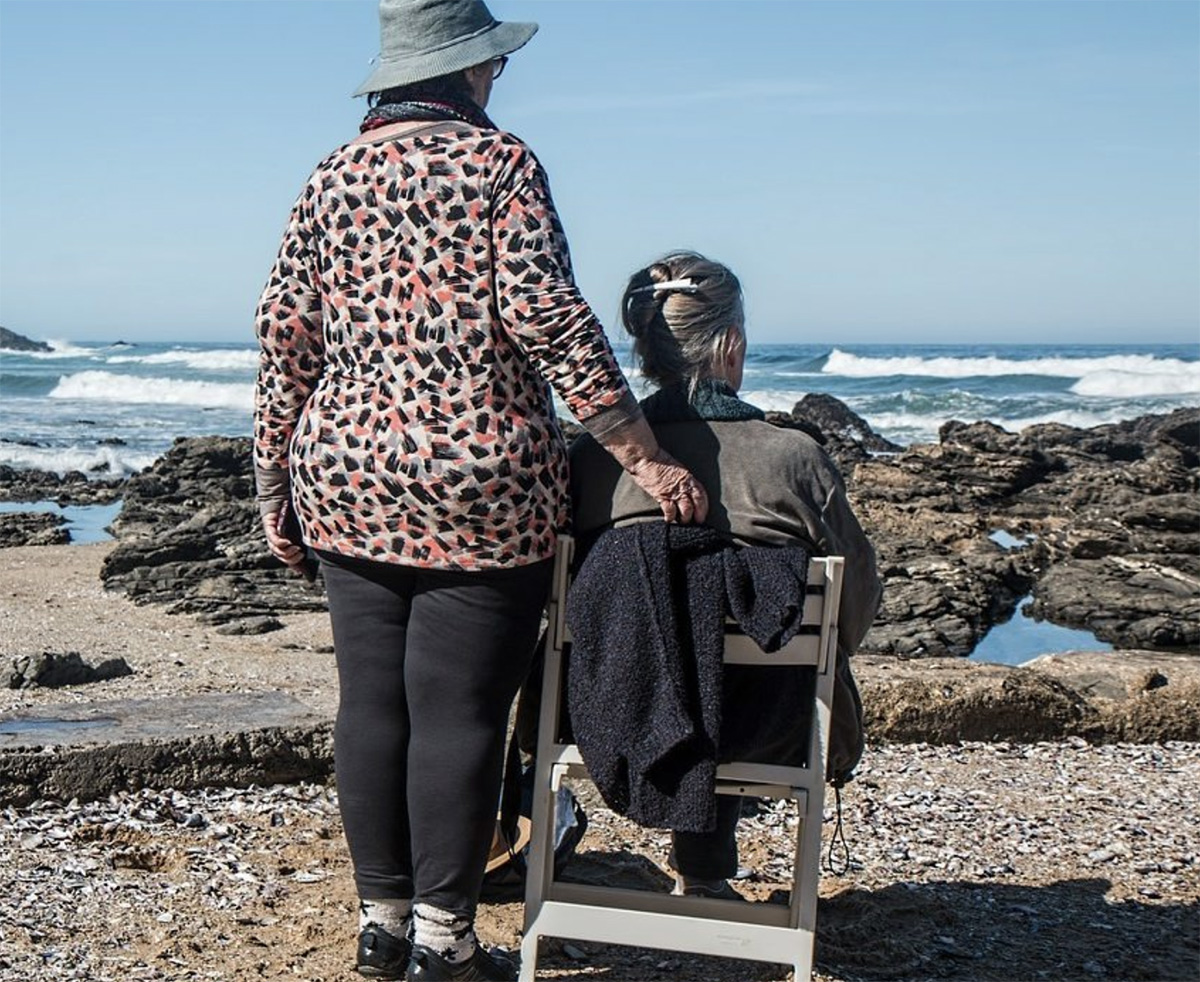 Tender Loving Care Two women on a beach one is being supportive
